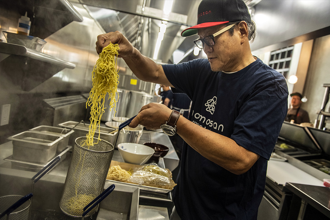 Chef pulling freshly cooked noodles from pot
